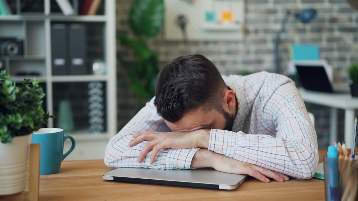 Person rubbing tired eyes at a computer